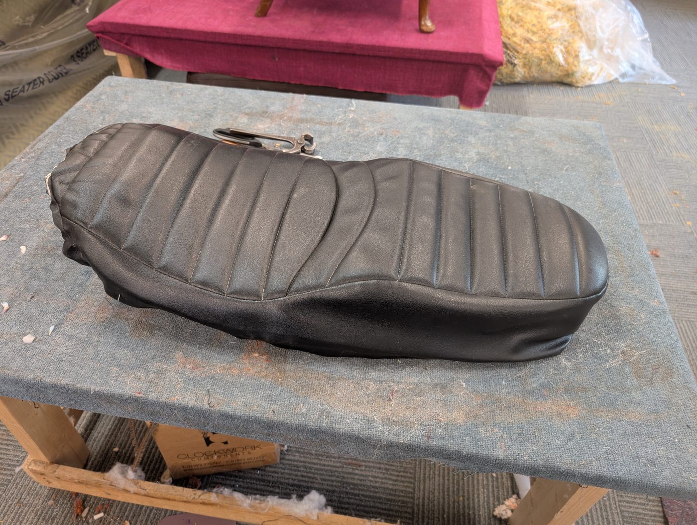 The seat as it came in — the original ribbed vinyl cover, tired and splitting at the nose.