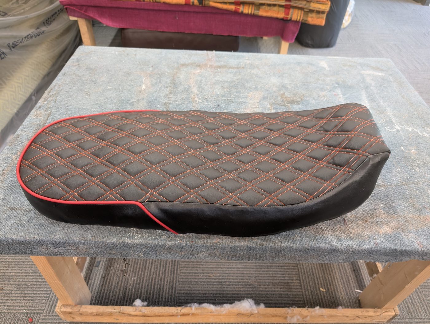 The finished cover fitted over the new foam — flat top, diamond stitching, red piping tracing the edge.