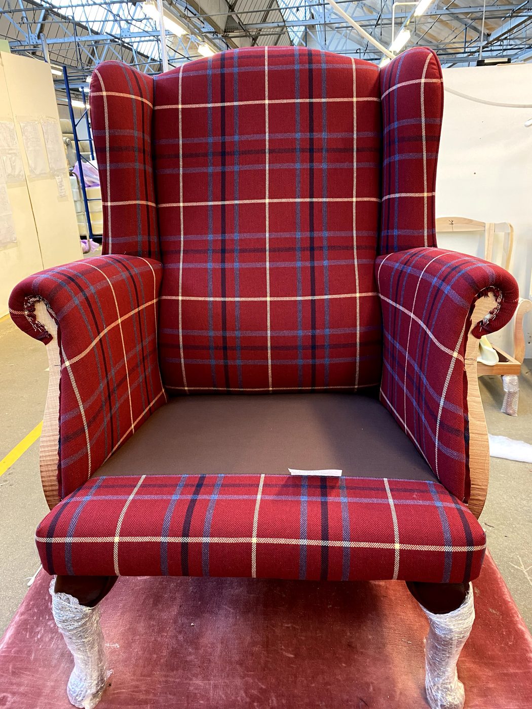 The elastic-webbed seat covered, its check aligned with the inside back so the lines flow down the chair and along the seat.
