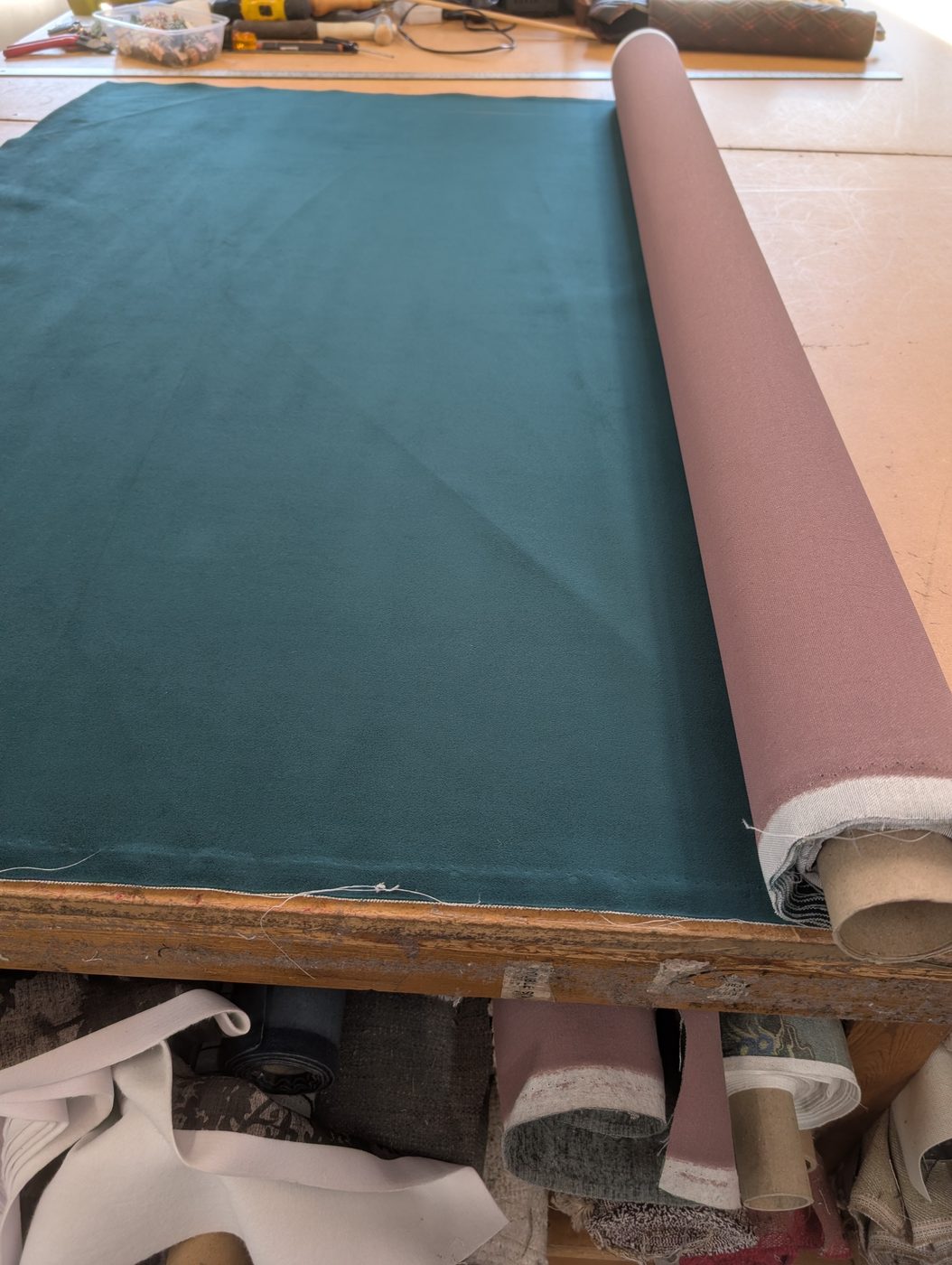 The teal velvet, rolled out on the bench ready to cut.