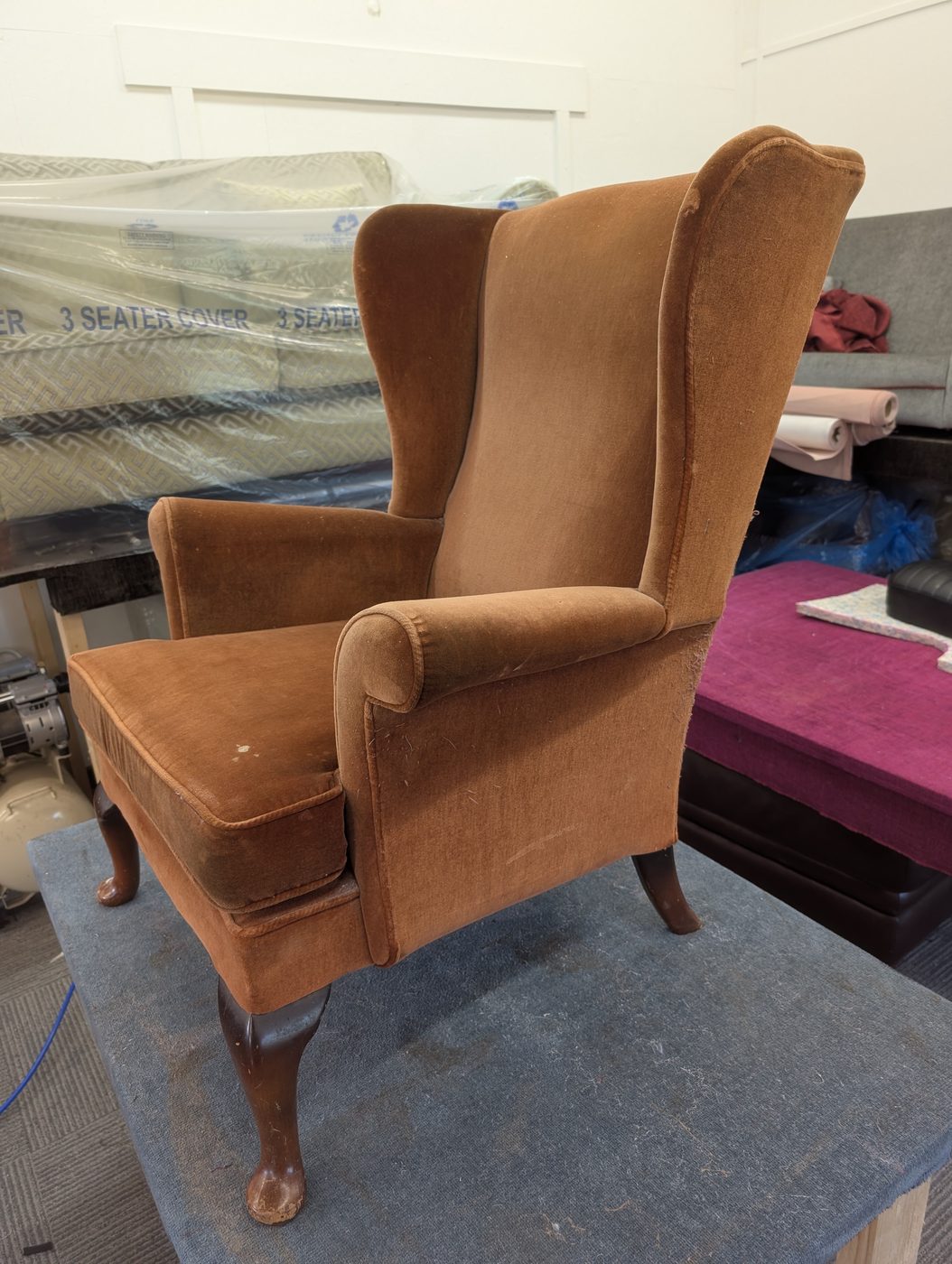 The arms and wings up close — the pile flattened on the leading edges where the chair gets handled.