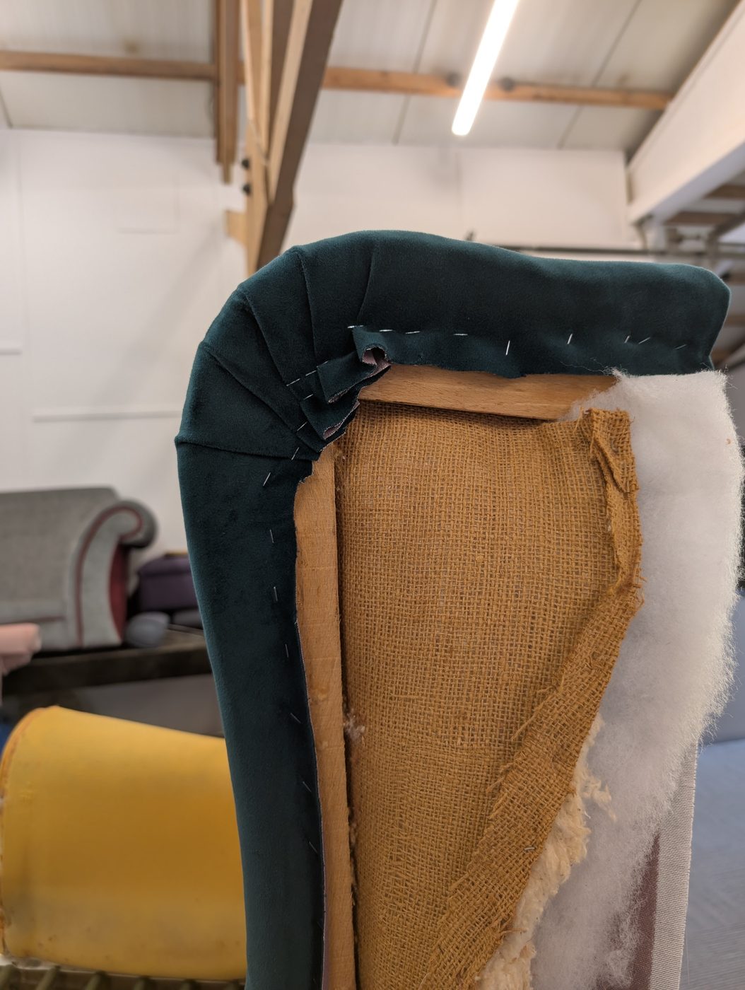 The first wing re-covered in the teal velvet — worked into the curve and pulled clean.