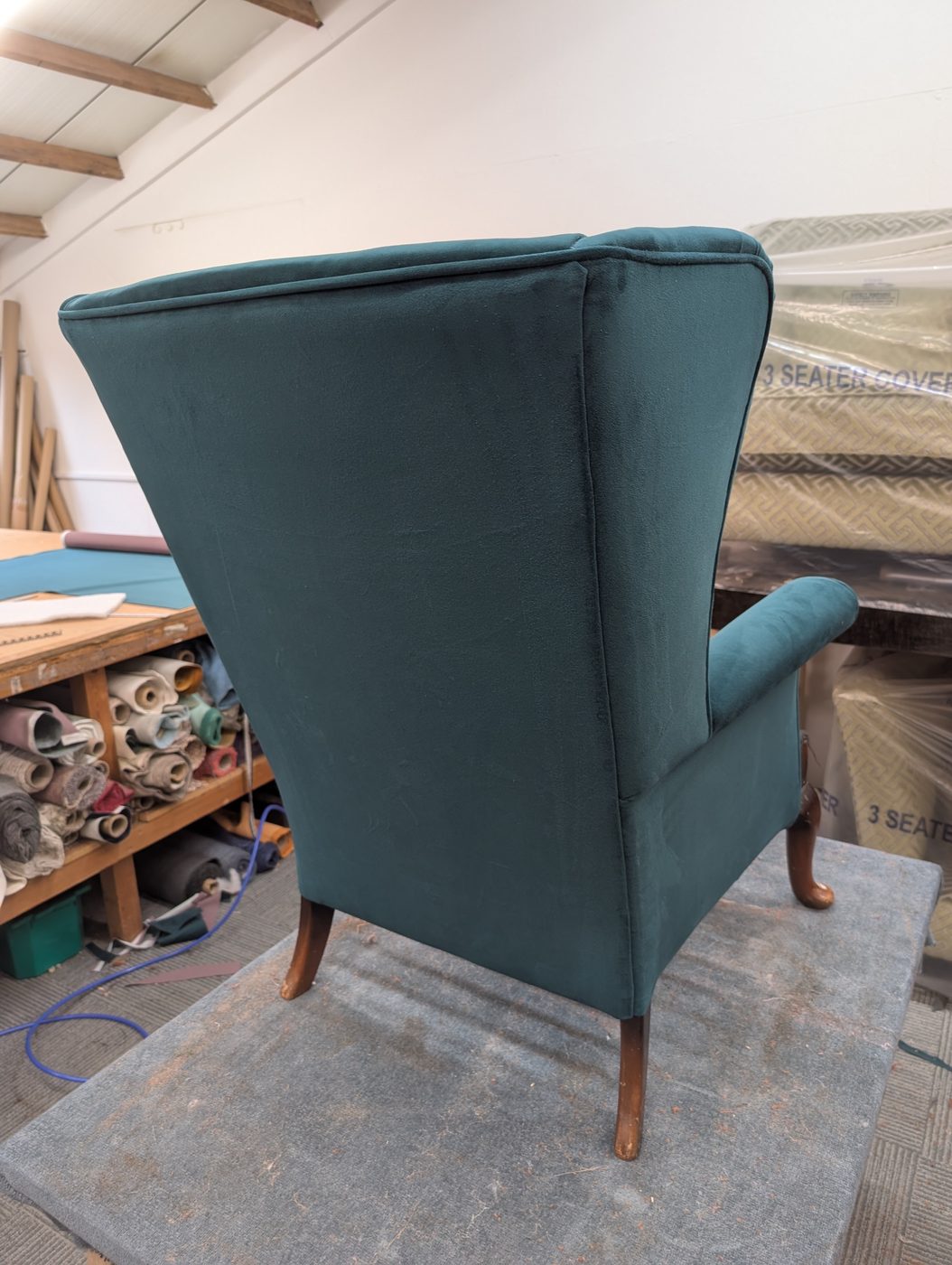The finished chair from behind — the outside back and wings clean, piped and taut.