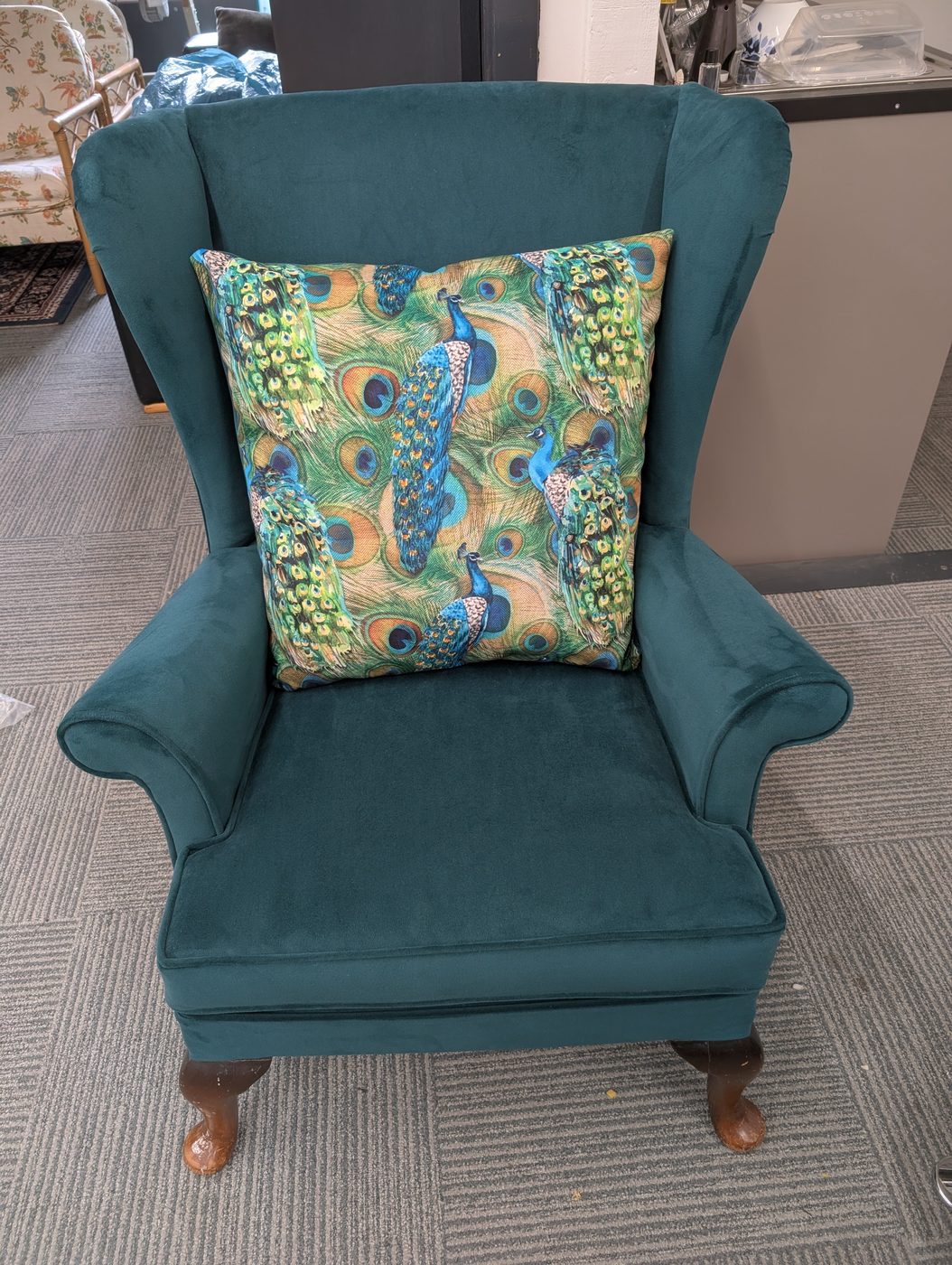 The finished chair with a free scatter cushion in a peacock print — the finishing flourish on every job.